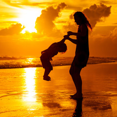 mother and  son playing on the beach at dawn time