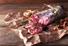 French Salami And Walnuts On Craft Paper On Wooden Background