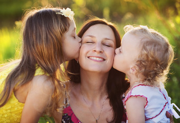 Happy mother with little daughters in nature