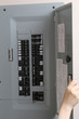 Woman checking automatic fuses at electrical control panel