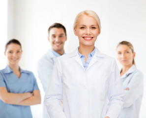 Canvas Print - smiling female doctor with group of medics