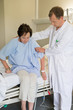 © onoky - Male doctor helping female patient to get up on hospital bed