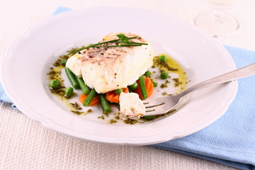 Cod fillet on fork with green beans, peas, parsley, olive oil