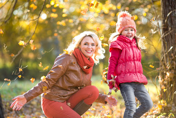 Happy parent and kid outdoor playing with autumn yellow leaves