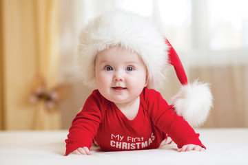 Wall Mural - funny Santa baby girl lying on white bed