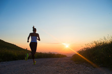 Woman Running On A Mountain Road At Summer Sunset