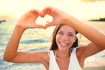 Wall Mural - Love vacation - woman showing heart on beach