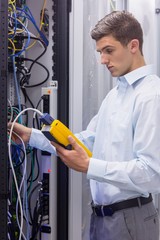 Poster - Focused technician using digital cable analyser on servers
