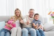© WavebreakmediaMicro - Happy family sitting on sofa giving thumbs up
