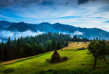 Wall Mural - amazing mountain landscape with fog and a haystack