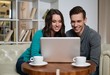 © Nejron Photo - Young couple with laptop and coffee behind table