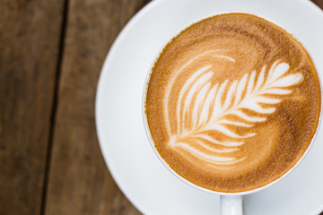 Wall Mural - Cup of hot latte art coffee on wooden table