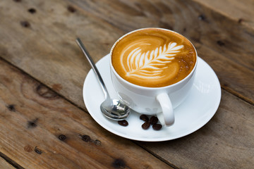 Cup of hot latte art coffee on wooden table