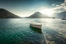 White Rowboat Moored At Bay Surrounded By Mountains