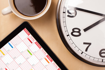 Wall Mural - tablet pc showing calendar on screen with a cup of coffee on a d