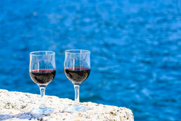 two glasses of red wine against the sea