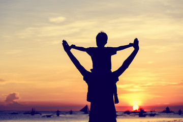 Wall Mural - happy father and son on sunset beach