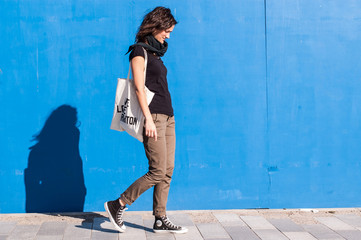 Wall Mural - Young girl dressed in brown chinos, sneakers on blue background