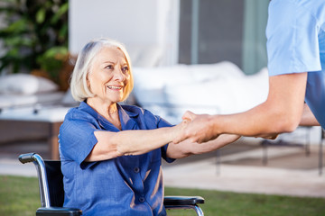 Wall Mural - Male Nurse Helping Senior Woman To Get Up From Wheelchair