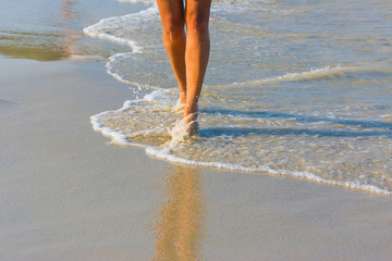 Wall Mural - Female leg walking on the beach