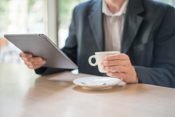 Man with tablet computer reading news at motning in cafe