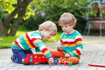 Wall Mural - Two siblings, kid boys playing with red school bus