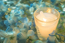 White Candle In Glass  With Blue Flowers On The Ground : Filtere