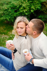 Young beautiful couple embracing under a blanket in the park. Te