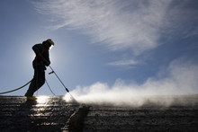Worker On Top Of Factory Hall, With High Pressure Washer