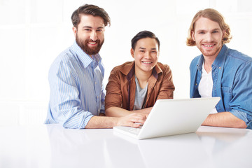 Wall Mural - Three handsome young men using a laptop