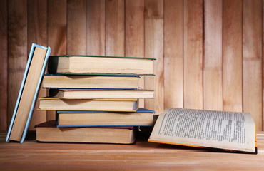 Books on wooden table on wooden wall background