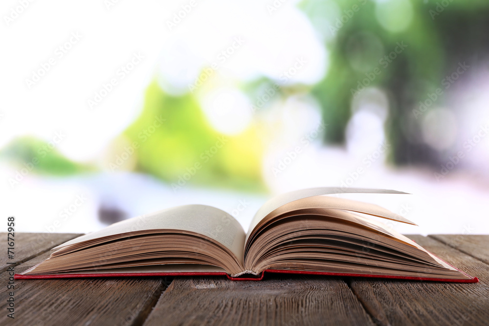 Open book on wooden table on natural background