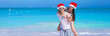 © travnikovstudio - Young romantic couple in Santa hats during beach vacation