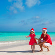© travnikovstudio - Little girl and happy dad in Santa Hat at exotic beach