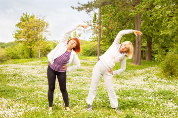 Two senior women exercise in the park