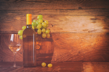 Glass of white wine with bottle and barrel on a rustic wooden ta