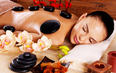 Wall Mural - Adult woman relaxing in spa salon with hot stones on back