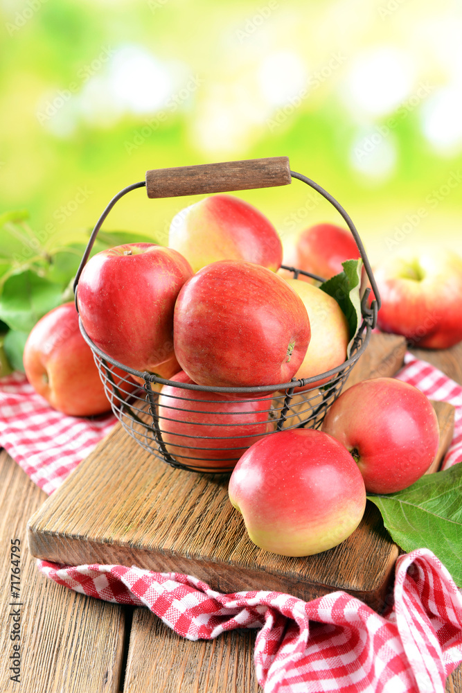 Sweet apples in wicker basket on table on bright background