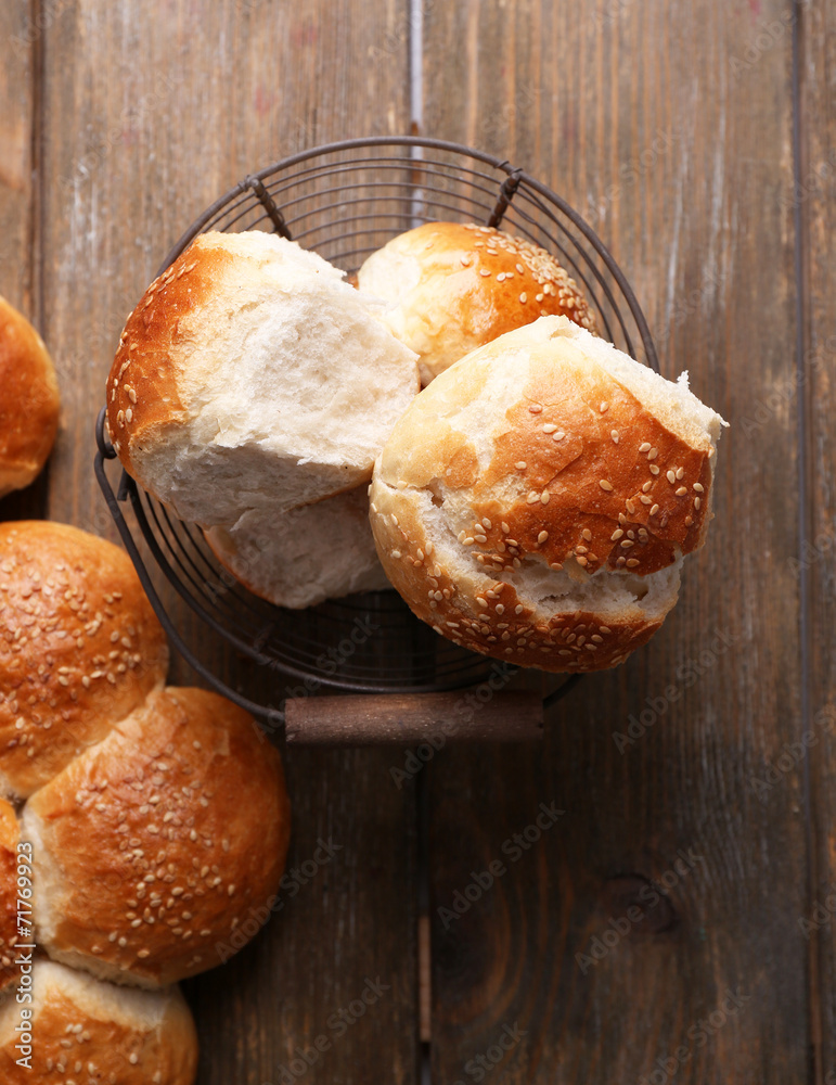 Tasty buns with sesame on color wooden background