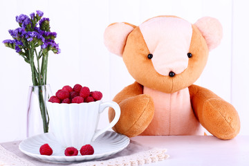 Wall Mural - Toy bear and cup of raspberries