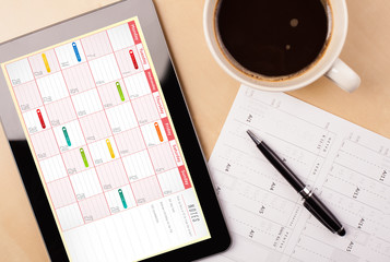 Wall Mural - tablet pc showing calendar on screen with a cup of coffee on a d