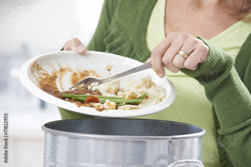 Fotomural Woman Scraping Food Leftovers Into Garbage Bin