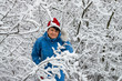 Woman in ski suit and cap of Santa Klaus  in snow-covered wood