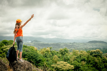 teenager with a backpack standing on a mountain top