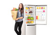 © Ljupco Smokovski - Woman holding a grocery bag by an open fridge