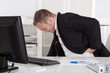 Business Mann mit Schmerzen im Büro: Rückenschmerzen