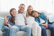 © WavebreakMediaMicro - Parents and children sitting together on couch