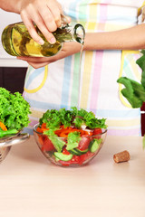 Wall Mural - Woman pouring olive oil in vegetable salad in kitchen