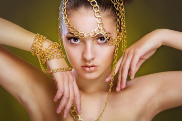 Girl with golden make-up and decoration of gold chains