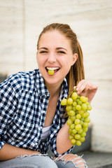 Wall Mural - Young woman eating  grapes